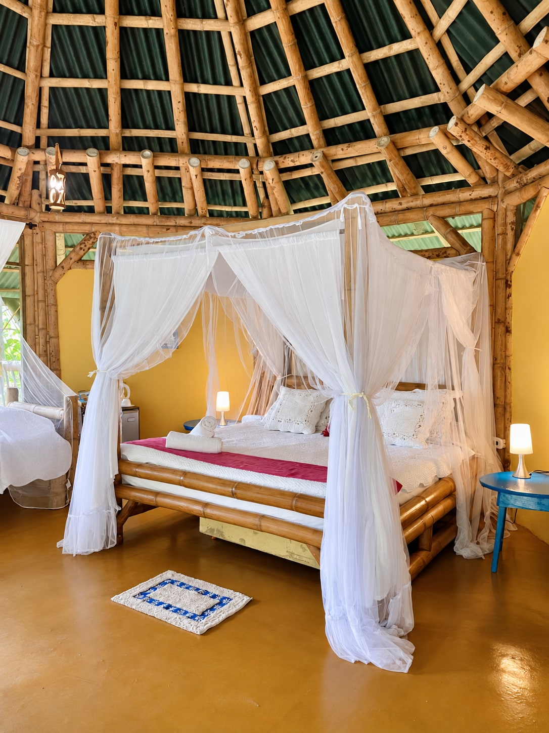 Habitación con cama bajo mosquitera y cúpula de guadua